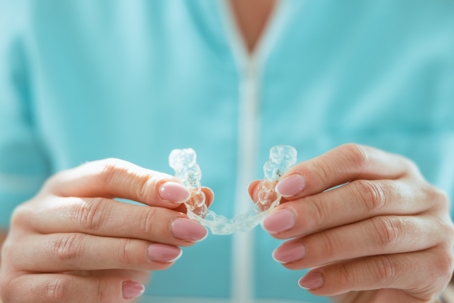 Close up of woman holding transparent teeth aligner